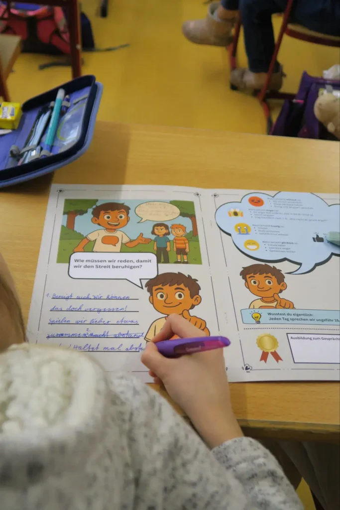 Schulkind schreibt in einem Stark.miteinander Arbeitsheft zu Kommunikation und Konfliktlösung im Klassenraum